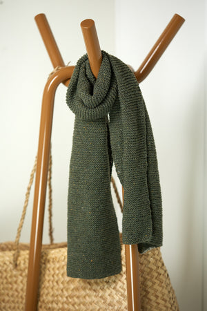 A long hand-knitted scarf in Forest Green hanging over a clothes rail.