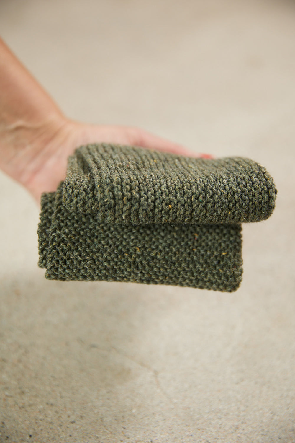 Small Handfulness kit in Forest Green: two balls of dark green yarn, wooden needles, a cotton bag and a kraft box.