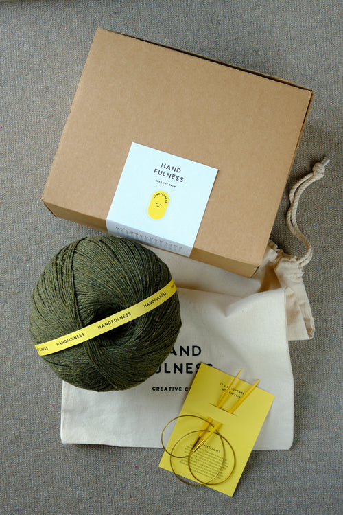 Large Handfulness kit in Forest Green: a ball of dark green yarn beside the kraft box and cotton bag.