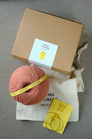 Large Handfulness kit in Rose: a ball of dusty pink yarn beside the kraft box and cotton bag.